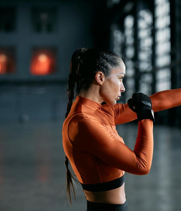 Young energetic woman performing dynamic cardio exercises in a dark studio.